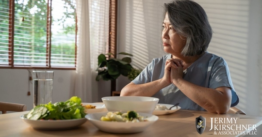Older Asian woman sitting at her kitchen table